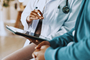 Close-up of a patient and doctor discussing test results on a tablet during a hospital consultation, reviewing possible causes of infertility